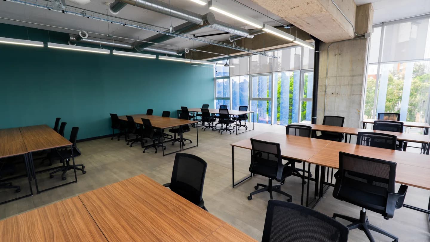 Espacio luminoso con mesas junto a los ventanales en Flexo Zapopan